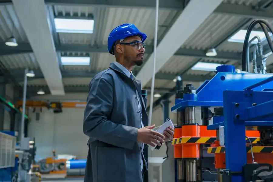 Técnico de capacete azul inspecionando máquina industrial