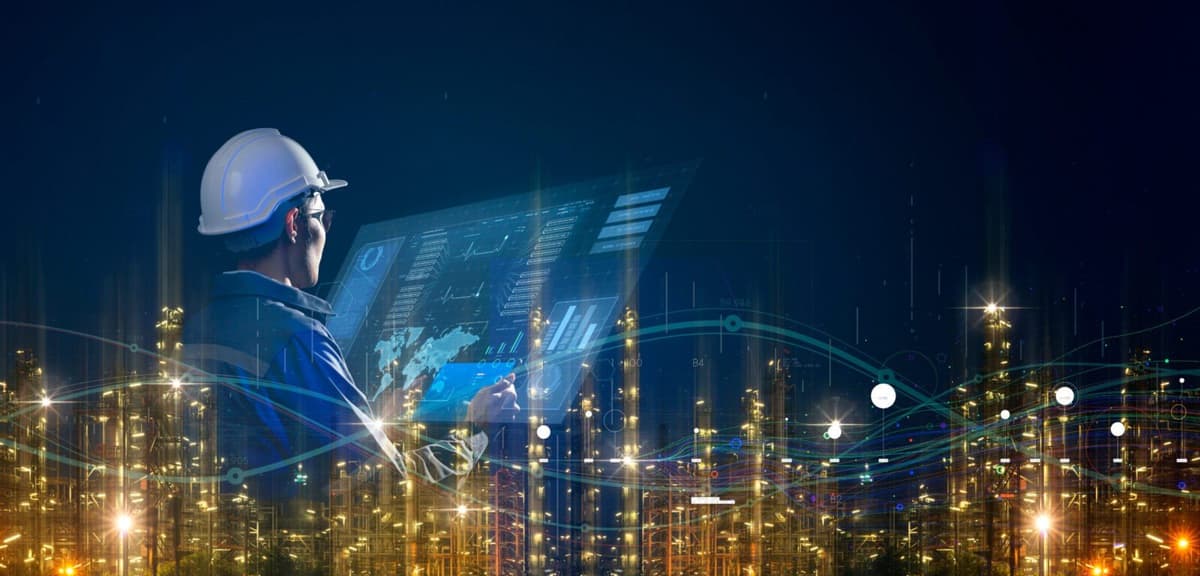 Engenheiro de capacete diante de painel digital de monitoramento da planta