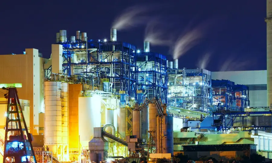 Planta de processo iluminada à noite, com torres e tubulações